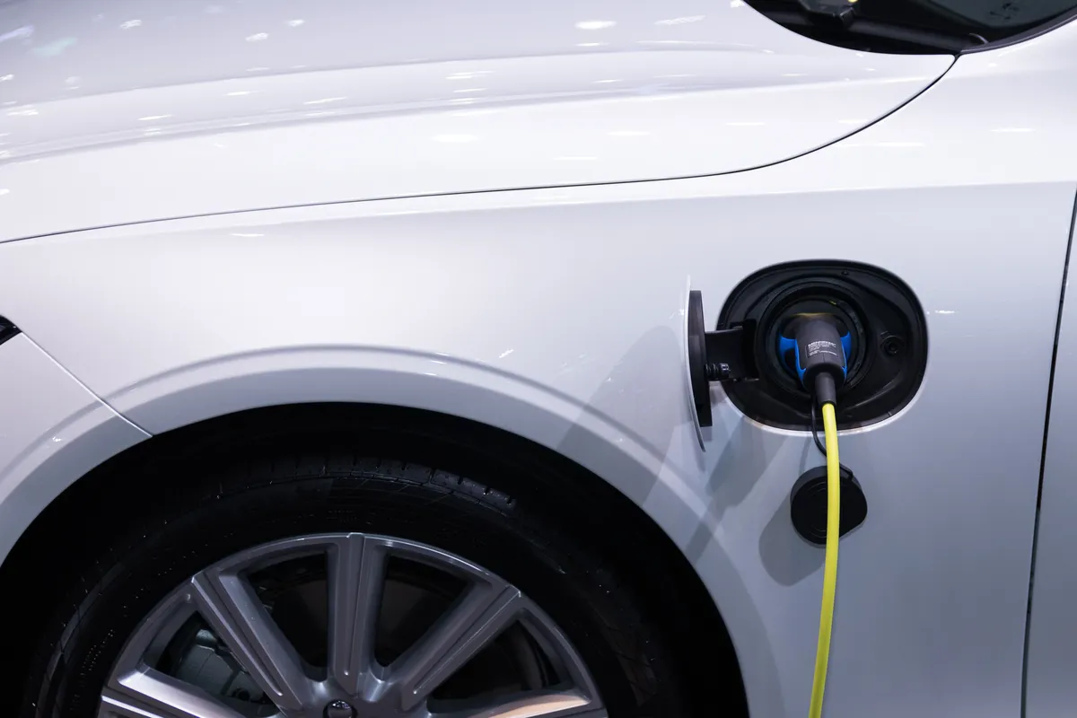 Cabo de carregamento ligado à tomada de um carro elétrico branco